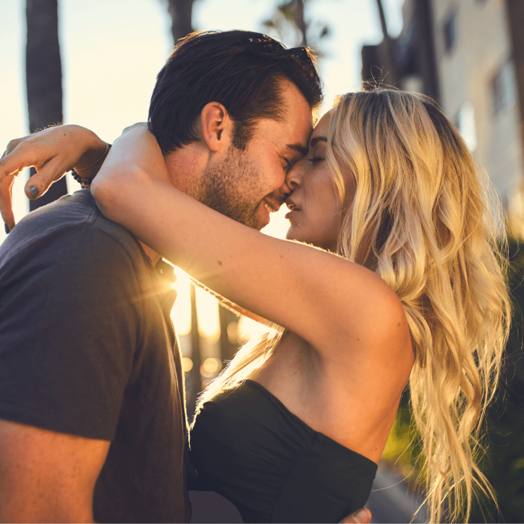 A couple sharing a passionate kiss under the evening sun. The woman has long blonde hair, and the man is dressed casually. The image evokes the success of dating strategies taught by Orlando's best dating coach, focusing on genuine connections and emotional intimacy.