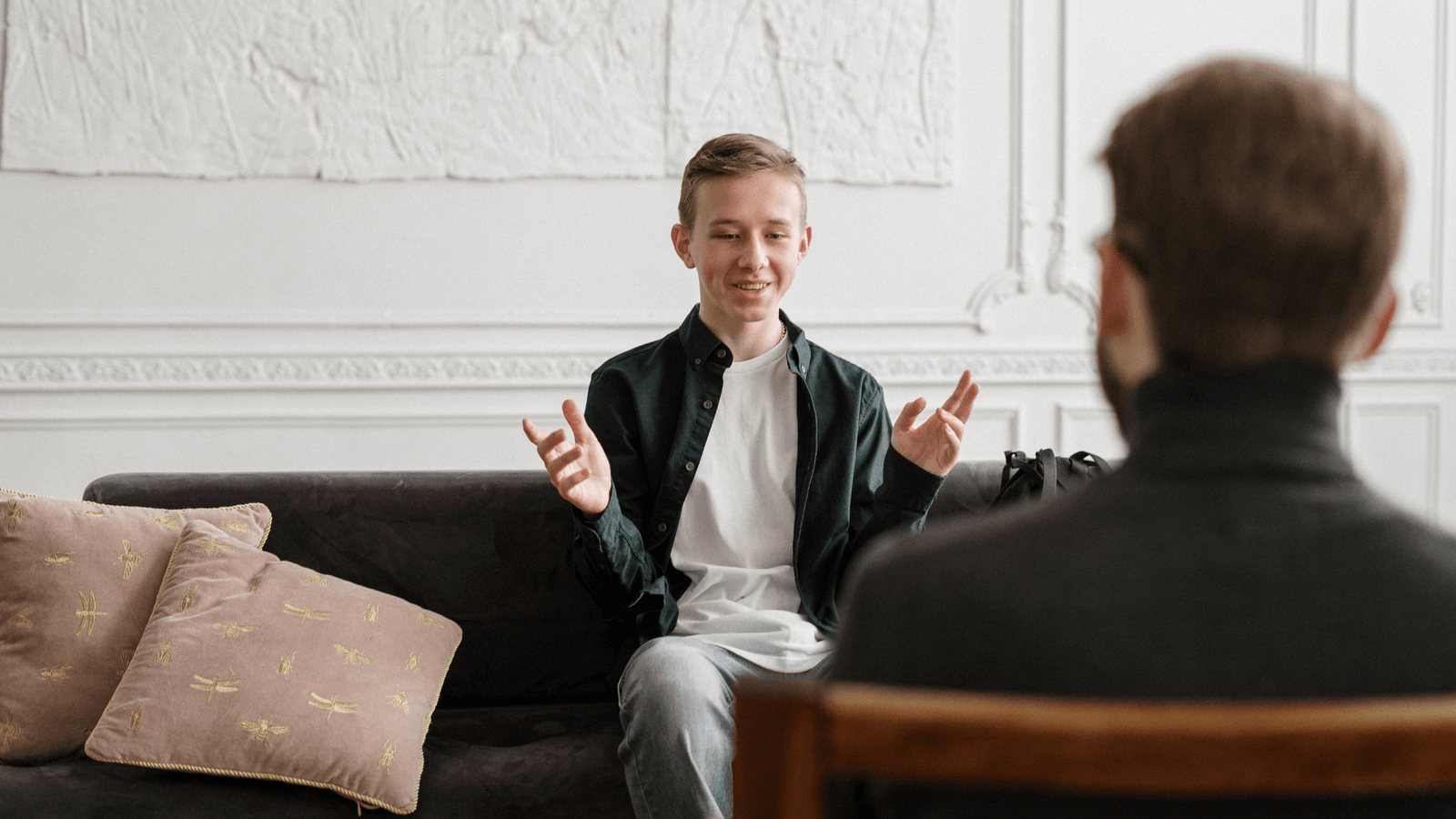 A young man sitting on a sofa, engaging in a lively conversation with a dating coach. The image emphasizes the supportive and engaging atmosphere of coaching sessions, offering practical dating tips and guidance. This photo represents Orlando's top dating coach, specializing in helping men improve their dating lives.