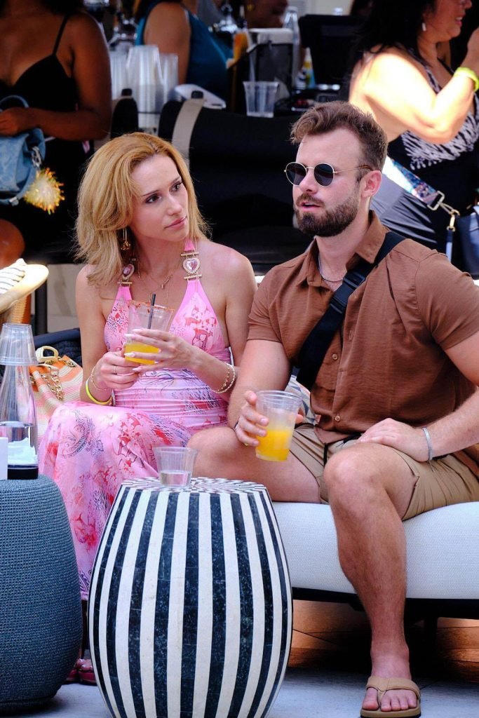 Ty Temmel, Orlando's top dating coach, engaged in a relaxed poolside conversation with a woman, both holding drinks and enjoying a sunny day. The image reflects the casual yet impactful nature of his dating coaching services.